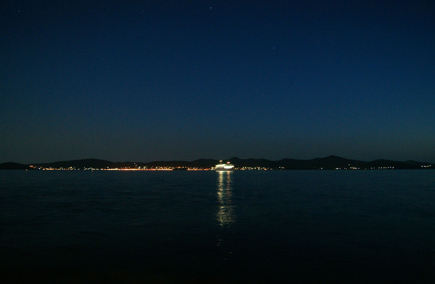 night landscape of ocean, mountains and city lights